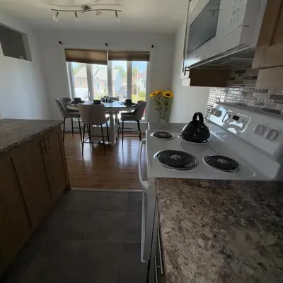 a kitchen with a white stove and a dining room at Apartment 3 chambres near Montréal in Sainte-Catherine