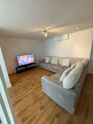 a living room with a couch and a flat screen tv at Apartment 3 chambres near Montréal in Sainte-Catherine