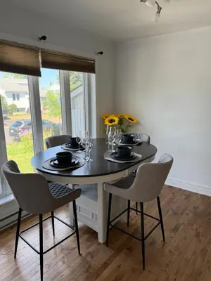 a dining room with a table with chairs and flowers at Apartment 3 chambres near Montréal in Sainte-Catherine