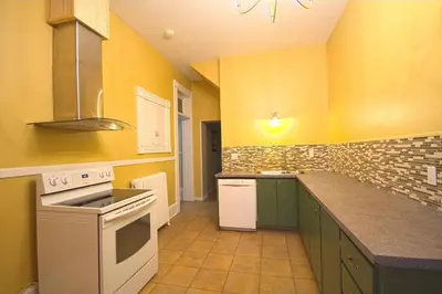 a kitchen with yellow walls and a white stove top oven at La Victorienne in Louiseville