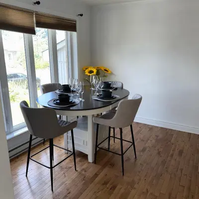 a dining room with a table with chairs and flowers at Chambre à louer proche de Montréal in Sainte-Catherine