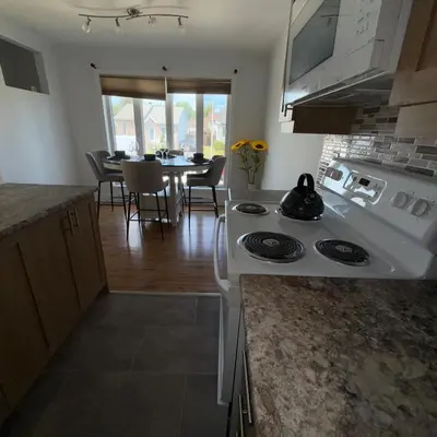 a kitchen with a white stove and a dining room at Chambre à louer proche de Montréal in Sainte-Catherine