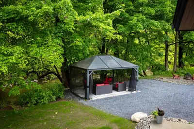 a black gazebo with red chairs in it at By the river - Le 91 in Frelighsburg