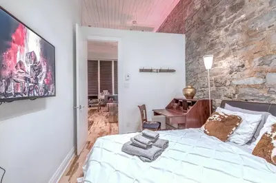 a bedroom with a bed and a stone wall at Old Port Elegance and Designer Loft with PV Terrace in Montréal