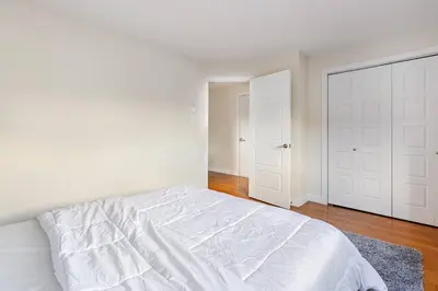 a white bedroom with a white bed and a door at Voltaire 2 Appartement 4,5 , 2ch Laval, Canada meublé in Laval