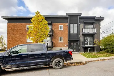 a blue truck parked in front of a building at Voltaire 2 Appartement 4,5 , 2ch Laval, Canada meublé in Laval