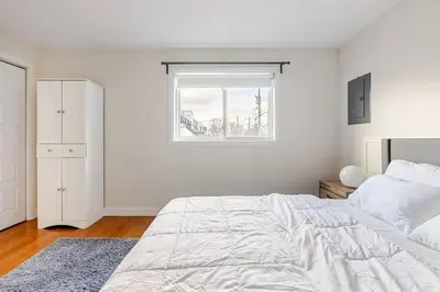 a white bedroom with a bed and a window at Voltaire 2 Appartement 4,5 , 2ch Laval, Canada meublé in Laval