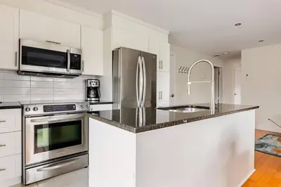 a kitchen with white cabinets and stainless steel appliances at Voltaire 2 Appartement 4,5 , 2ch Laval, Canada meublé in Laval