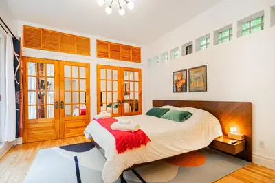 a bedroom with a large bed with a red blanket at Unique Downtown Montreal Stay with Private Terrace in Montréal