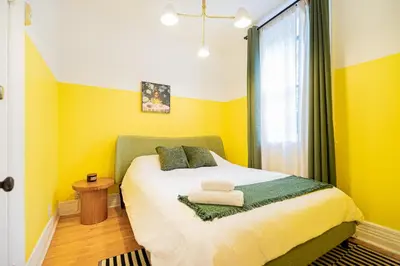 a bedroom with a bed with yellow walls and a window at Unique Downtown Montreal Stay with Private Terrace in Montréal