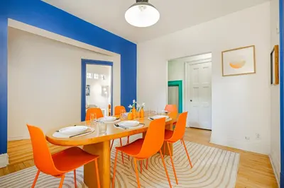 a dining room with a wooden table and orange chairs at Unique Downtown Montreal Stay with Private Terrace in Montréal