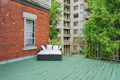 a patio with a white couch on a wooden deck at Unique Downtown Montreal Stay with Private Terrace in Montréal