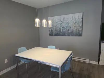 a dining room with a white table and blue chairs at Cozy Digital Nomad Apartment in Montreal Riv-Sud in Brossard