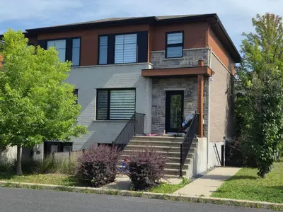 a large house with a staircase in front of it at Cozy Digital Nomad Apartment in Montreal Riv-Sud in Brossard