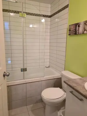 a bathroom with a shower and a toilet and a tub at Cozy Digital Nomad Apartment in Montreal Riv-Sud in Brossard