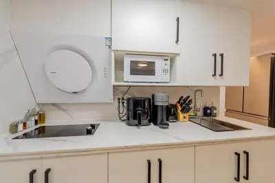 a white kitchen with a sink and a microwave at Modern Studio-Patio & BBQ-Parking Included in Montréal