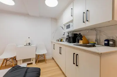 a kitchen with white cabinets and a table and chairs at Modern Studio-Patio & BBQ-Parking Included in Montréal