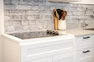 a white kitchen with a brick wall at Theatre Hotel by Lodgo in Montréal