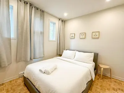 a bedroom with a bed with white sheets and a window at Lovely One-Bedroom in Vibrant Plateau Mont-Royal in Montréal