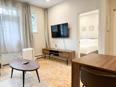 a living room with a television and a bed at Lovely One-Bedroom in Vibrant Plateau Mont-Royal in Montréal