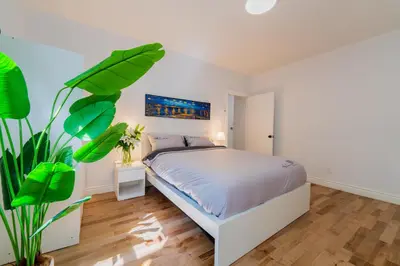a white bedroom with a bed and a plant at Newly Renovated 3BR 2BA Spacious and Modern in Montréal