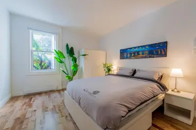 a white bedroom with a bed and a window at Newly Renovated 3BR 2BA Spacious and Modern in Montréal