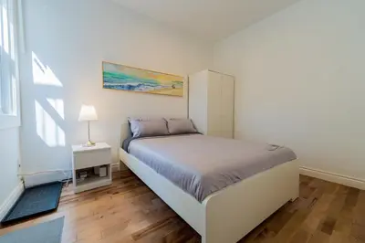 a white bedroom with a bed and a window at Newly Renovated 3BR 2BA Spacious and Modern in Montréal