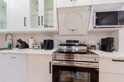 a kitchen with white cabinets and a stove top oven at Newly Renovated 3BR 2BA Spacious and Modern in Montréal