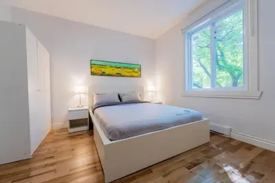 a white bedroom with a bed and a window at Newly Renovated 3BR 2BA Spacious and Modern in Montréal