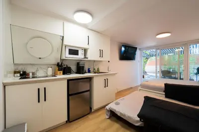 a kitchen with white cabinets and a living room at Renovated Studio w Parking Queen Bed and Sofa Bed in Montréal