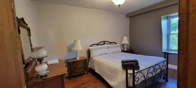a bedroom with a bed and two lamps and a window at Manoir Hunting 1869 in Waterville