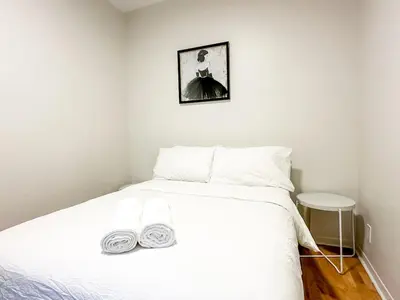a bedroom with a white bed and a picture on the wall at Chic & Fully Furnished 2-Bedroom Apartment in Prestigious Westmount in Montréal