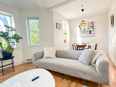 a living room with a couch and a table at Chic & Fully Furnished 2-Bedroom Apartment in Prestigious Westmount in Montréal