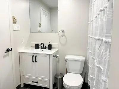 a white bathroom with a toilet and a sink at Chic & Fully Furnished 2-Bedroom Apartment in Prestigious Westmount in Montréal
