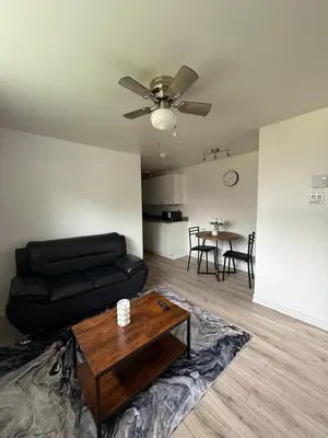a living room with a black couch and a table at Studio, Near Montreal in Repentigny