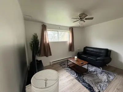 a living room with a black leather couch and a table at Studio, Near Montreal in Repentigny
