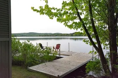 a dock on a lake with two chairs on it at Mirror Lakefront and SPA - A Fleur D'eau in Dudswell