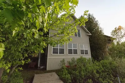 a house with a table and chairs in the yard at Mirror Lakefront and SPA - A Fleur D'eau in Dudswell