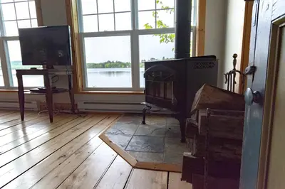a living room with a fireplace and a television at Mirror Lakefront and SPA - A Fleur D'eau in Dudswell