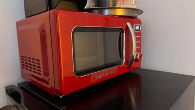 a red microwave sitting on top of a table at 2 min from Bell Center, Downtown & metro station in Montréal