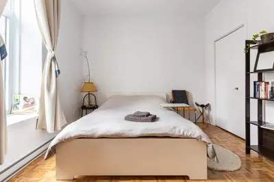 a white bedroom with a bed and a window at 2 min from Bell Center, Downtown & metro station in Montréal