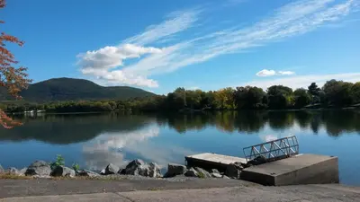 a bench sitting on the side of a lake at Bright 2BR Near River Private Parking in McMasterville