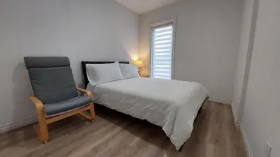 a bedroom with a bed and a chair and a window at Bright 2BR Near River Private Parking in McMasterville