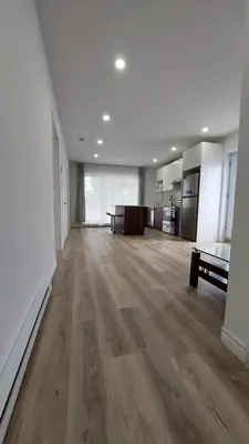 an empty living room with wooden floors and a kitchen at Bright 2BR Near River Private Parking in McMasterville
