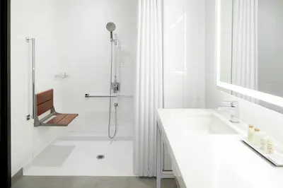 a white bathroom with a shower and a sink at Renaissance Montreal Downtown Hotel in Montréal