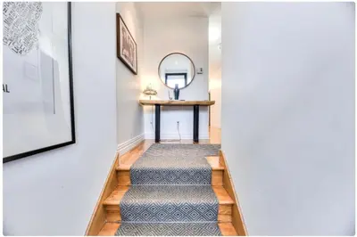 a hallway with stairs with a table and a mirror at Condo lumineux au cœur du Mile-end in Montréal