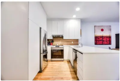 a kitchen with white cabinets and a wooden floor at Condo lumineux au cœur du Mile-end in Montréal