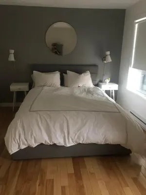 a bed with a white comforter and a mirror at Lovely 2 bedroom in little burgandy in Montréal