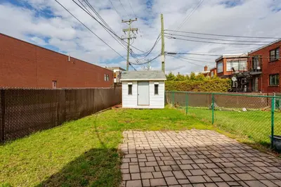 a small white house in a yard next to a fence at Cozy 2 bedroom close to downtown in Montréal