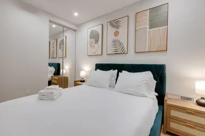 a bedroom with a white bed and some pictures on the wall at Spacious 1BDR unit with Private Patio and Parking by M11 in Montréal